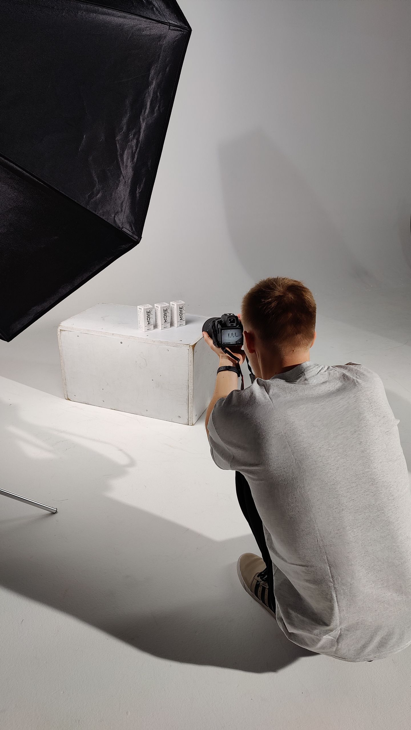 A photographer setting up for a product photoshoot in a professional studio environment.